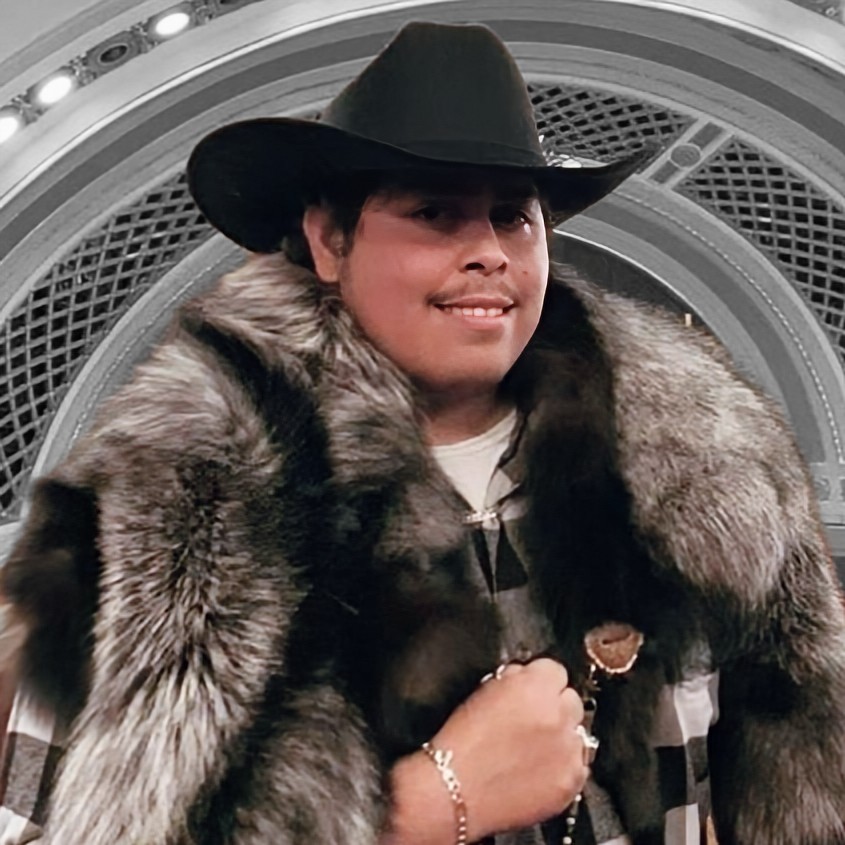 Vincent wearing a black vaquero (cowboy) hat and a silver fox fur. He has his hand in a fist shape, a habit picked up from his time boxing as a youth.